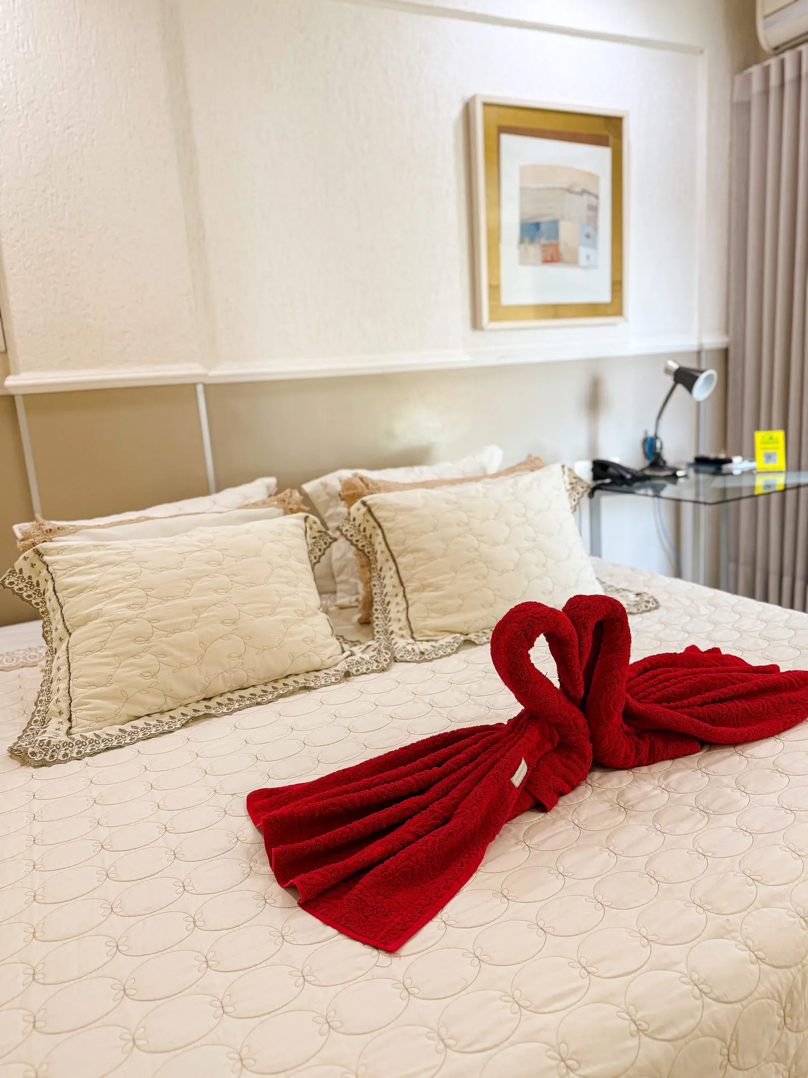 Cama de casal arrumada com toalhas vermelhas dobradas em forma de cisne