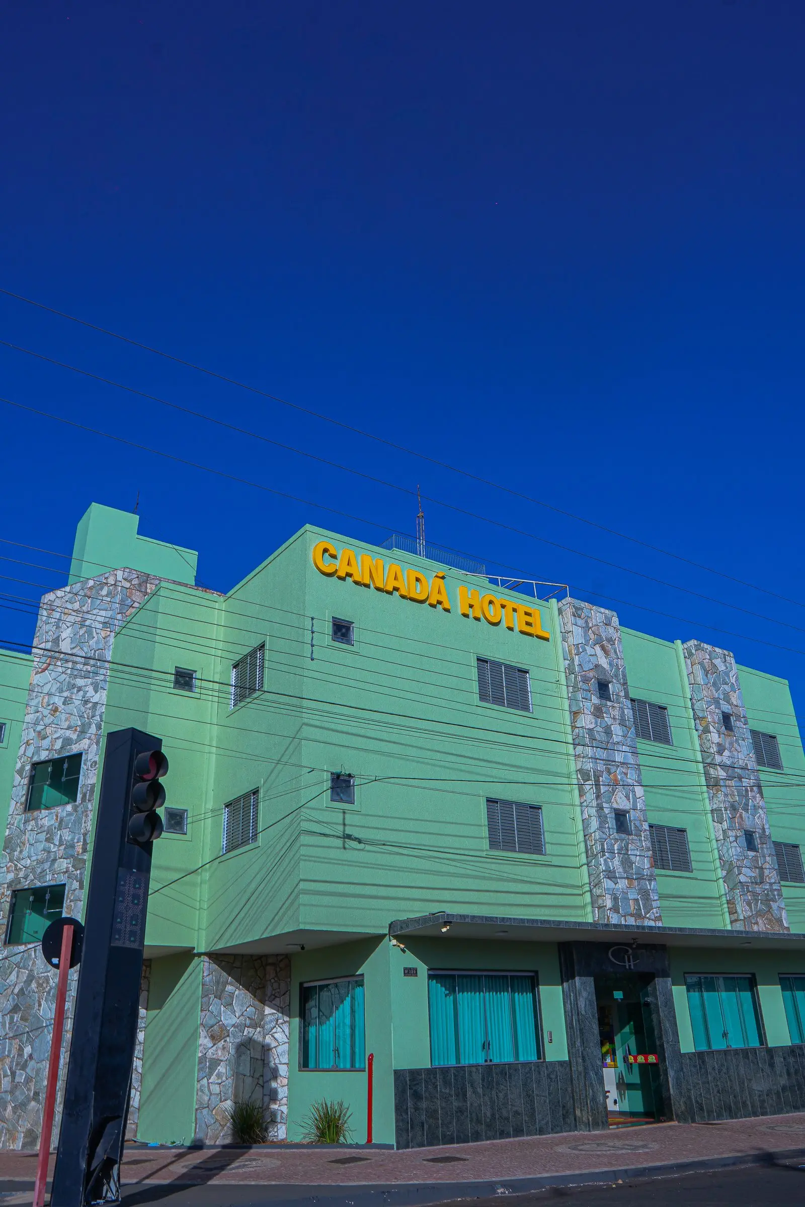 Fachada do Canadá Hotel vista de baixo, com o letreiro amarelo sob céu azul