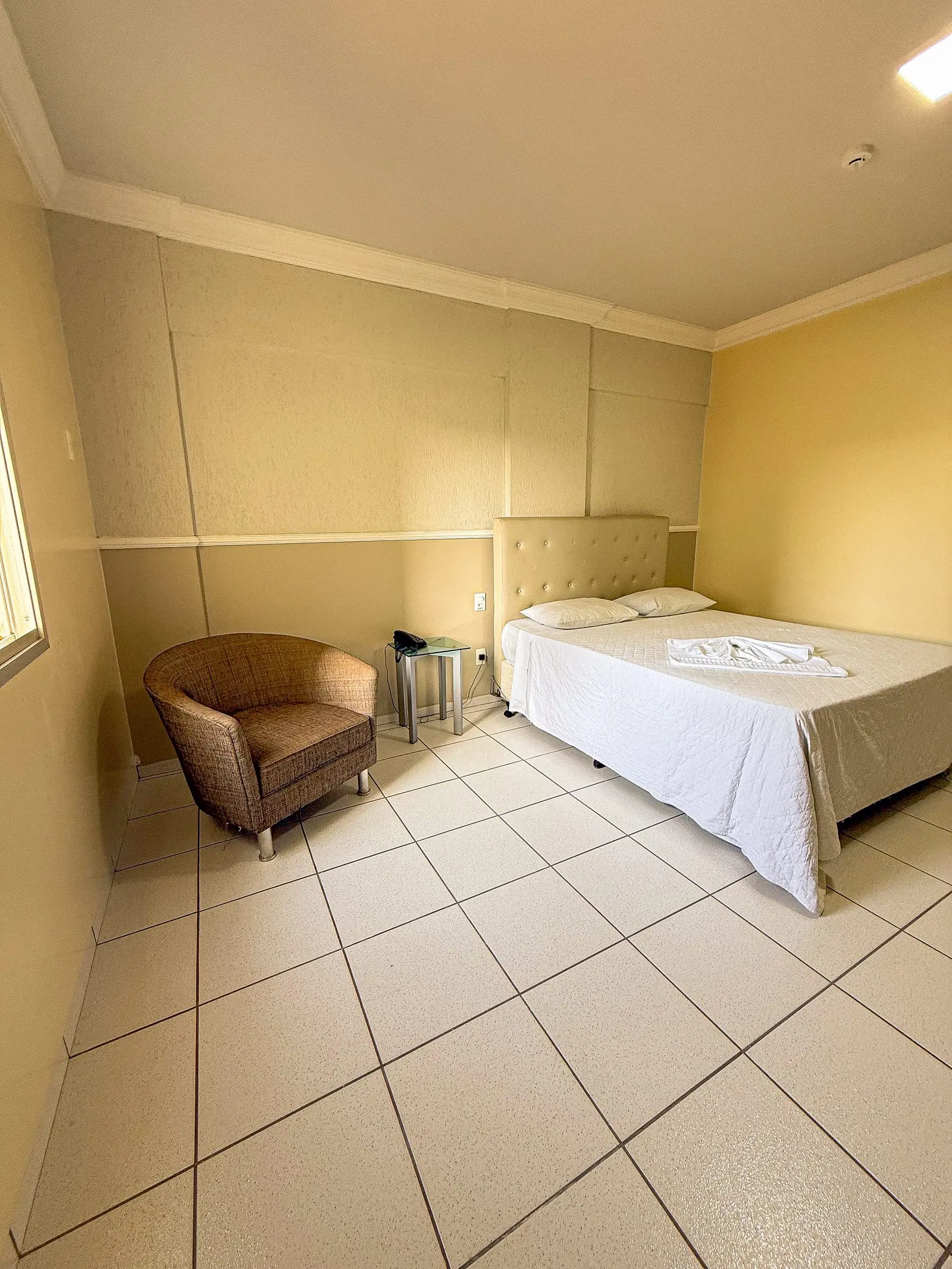 Quarto Individual com cama de casal, poltrona e luz natural