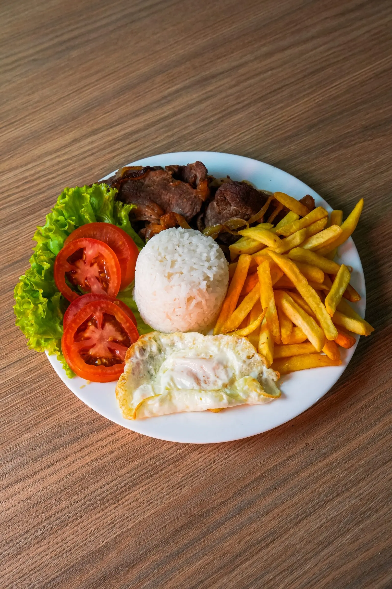 Prato com carne, arroz, batata frita, ovo e salada