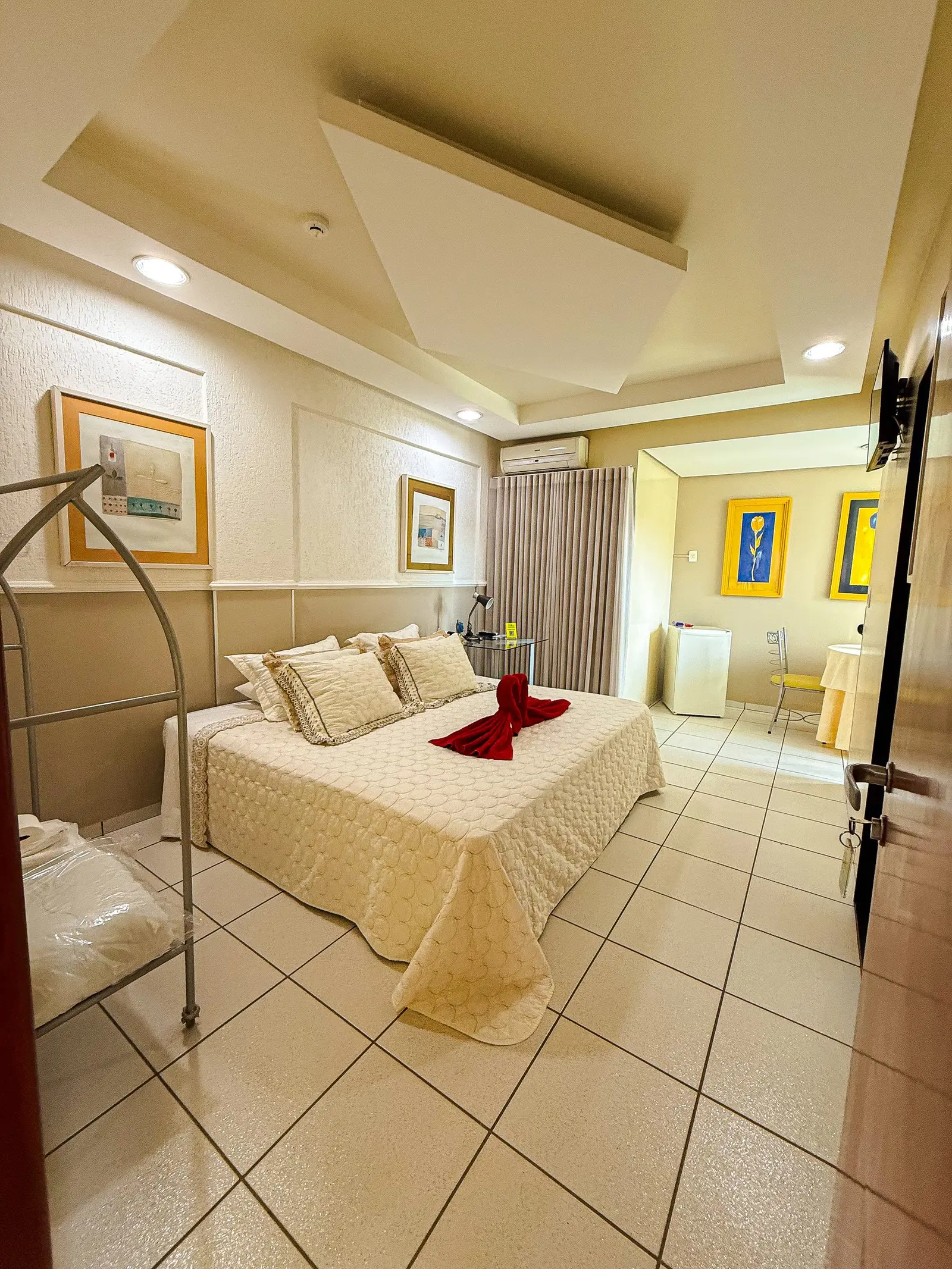 Suíte Master com cama king size, toalhas vermelhas e acesso à sacada