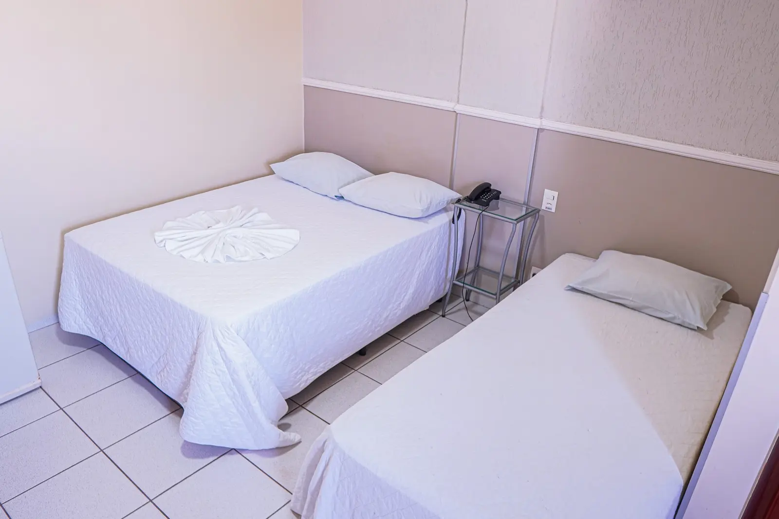 Camas do quarto Triplo com enxoval branco e telefone na cabeceira